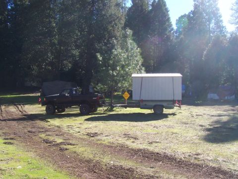 1994 Ford F-150 - A black 1994 Ford F-150 is seen from the side, towing a large white cargo trailer through a grassy, wooded area.