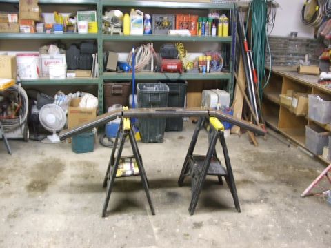 1990 Chevrolet Suburban - A metal frame is assembled on two sawhorses in a cluttered garage setting.