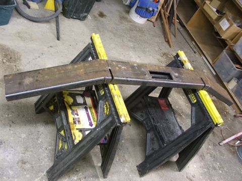1990 Chevrolet Suburban - A fabricated metal bumper rests on black and yellow sawhorses in a workshop setting.