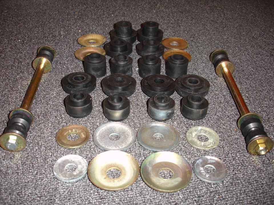 Collection of black rubber suspension bushings and metal washers on a carpeted surface
