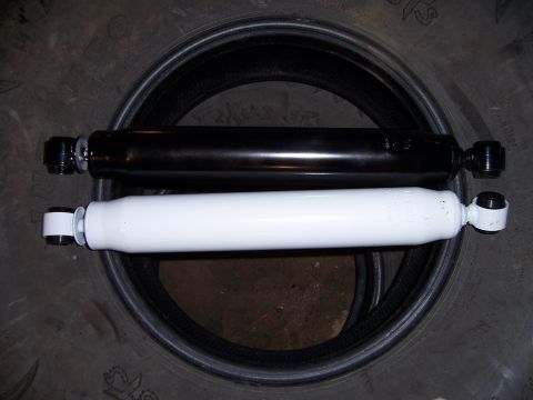 1983 Ford Bronco - Two shock absorbers, one black and one white, are displayed on top of a tire.