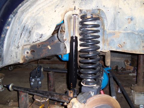 1983 Ford Bronco - Close-up of vehicle suspension components, including a shock absorber and coil spring, with a visible website logo.