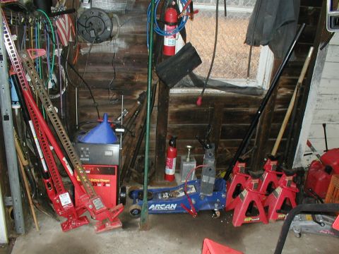 1979 Ford Bronco - A cluttered garage scene displays various automotive tools and equipment, including jacks and a battery charger.