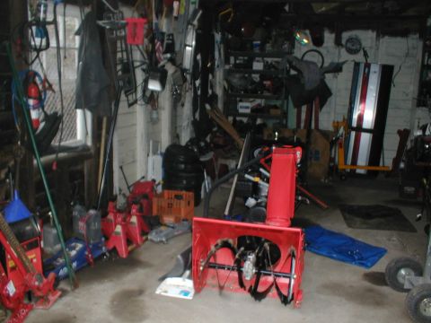 1979 Ford Bronco - Garage scene filled with tools, equipment, and a snowblower, no vehicles are clearly visible.