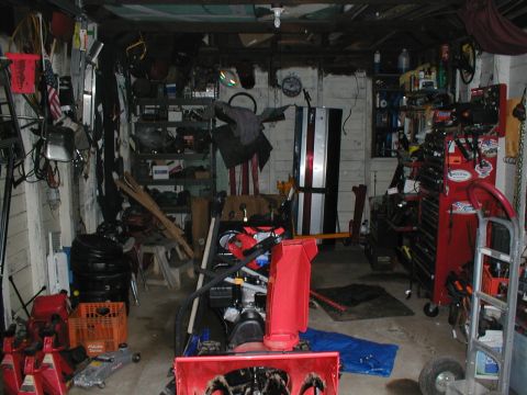 1979 Ford Bronco - This cluttered garage contains tools, equipment, and a snowblower, but no visible 1979 Ford Bronco.