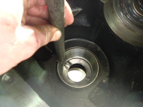 1989 Ford Bronco - A hand manipulates a tool within a mechanical assembly, focusing on internal components.