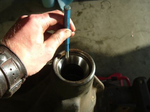 1989 Ford Bronco - Close-up of a hand using a punch on a metal housing, likely for a vehicle repair.