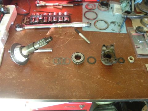 1989 Ford Bronco - Various automotive differential components and repair tools are organized on a wooden workbench surface.