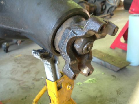 1989 Ford Bronco - Close-up of a driveshaft universal joint supported by a jack stand, with workshop items visible in the background.