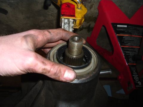 1989 Ford Bronco - Mechanic's hand holding a splined shaft over a housing, with a jack stand visible.