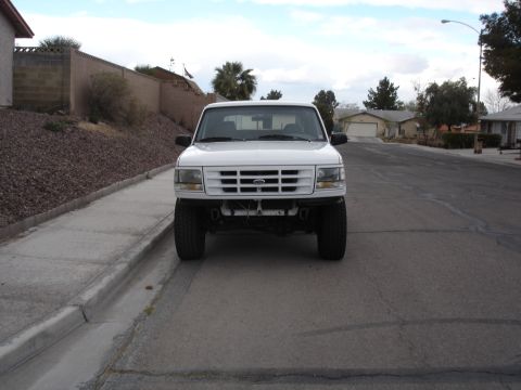 1996 Ford Bronco - A white Ford pickup truck is parked on a residential street, facing the camera. The truck appears to be lifted.