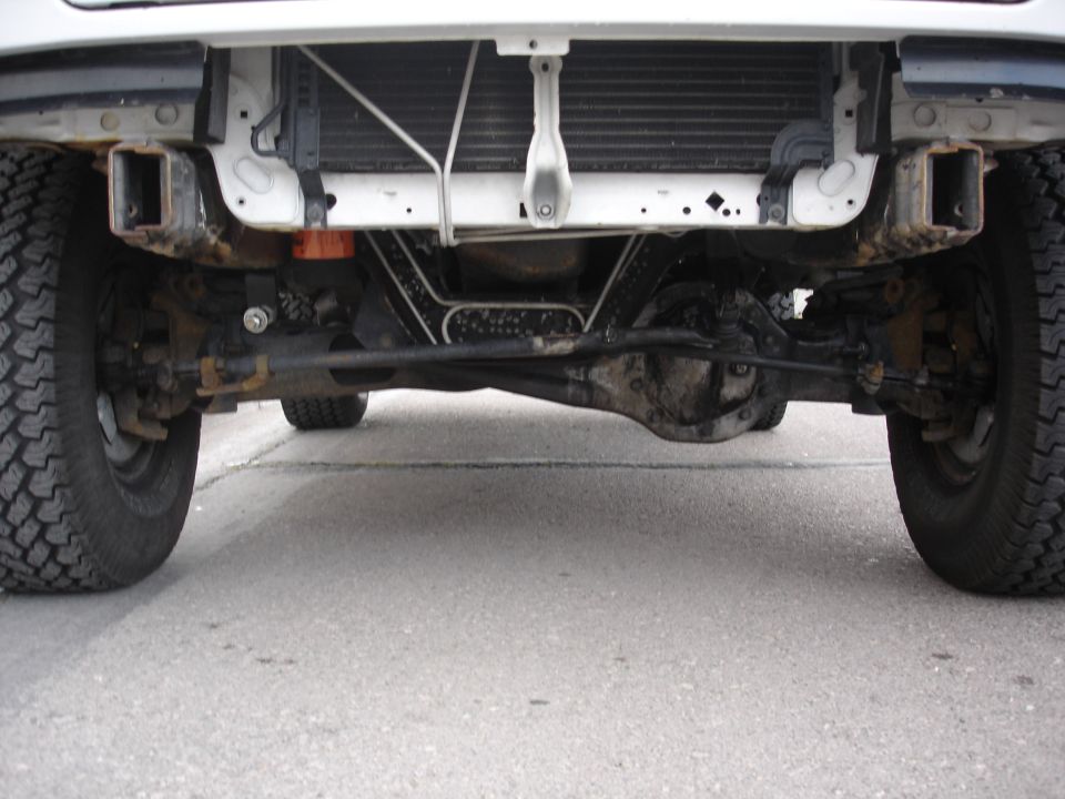 Underside front axle and differential of a white Ford Bronco viewed from ground level