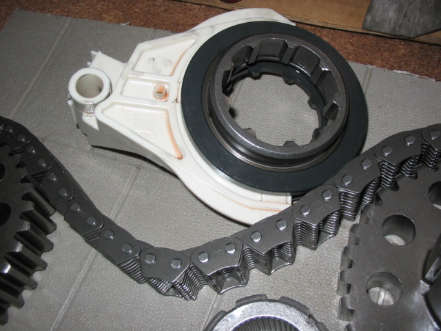 Transfer case parts: white housing, drive chain, and sprockets on foam mat.