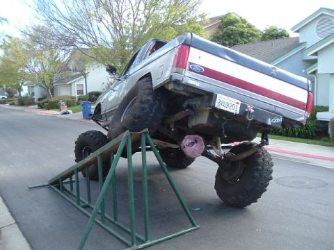 1989 Ford Bronco - Modified 1989 Ford Bronco on ramps, showing its undercarriage and large tires.