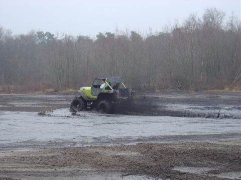 1987 Suzuki Samurai - Off-road vehicle navigates a muddy terrain, creating a large spray of mud.