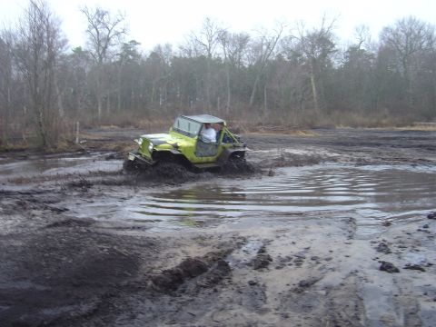 1987 Suzuki Samurai - A driver navigates a muddy terrain in a vintage Jeep CJ-5.