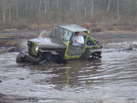 1987 Suzuki Samurai - An off-road vehicle is stuck in muddy water with steam rising from the engine.