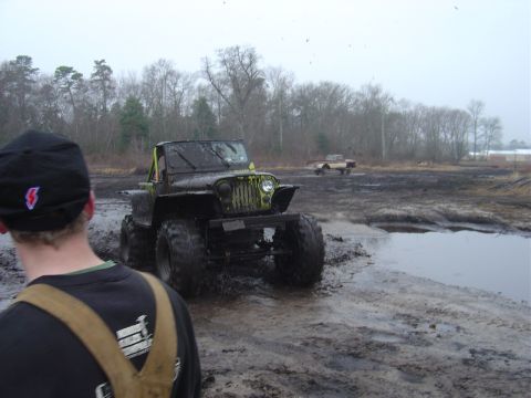 1987 Suzuki Samurai - A heavily modified Jeep navigates a muddy terrain, with another vehicle visible in the distance.