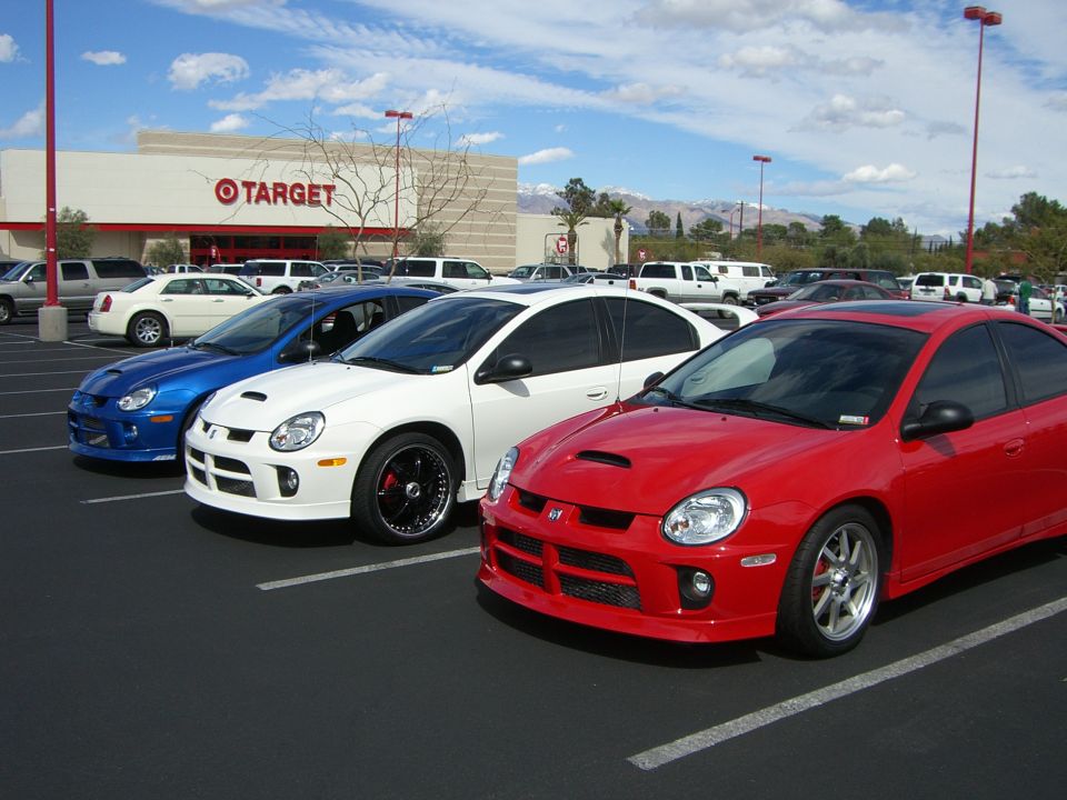 Three Dodge Neon SRT-4s parked in a lot in front of a Target store. Red, white, and blue