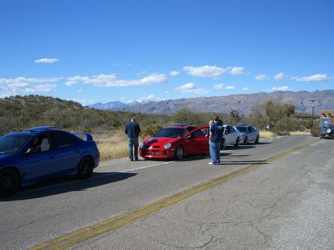 1996 Ford Probe - Several Dodge Neon SRT-4s are parked along a road with mountains in the background.