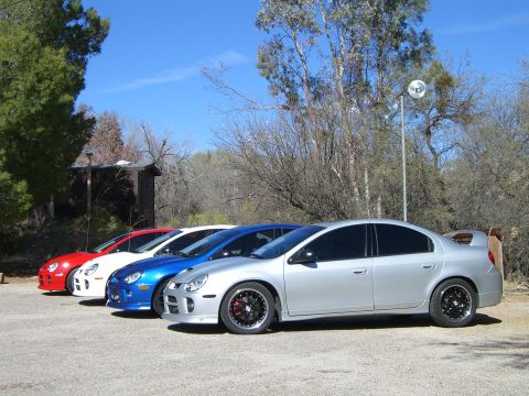1996 Ford Probe - A line of four cars, including a silver Dodge Neon SRT-4, parked outdoors on a sunny day.