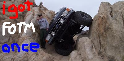 1989 Ford Bronco - A 1989 Ford Bronco is shown tipped on its side while navigating rocky terrain.
