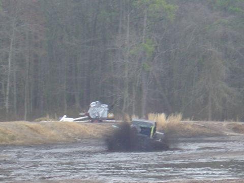 1987 Suzuki Samurai - A vehicle is stuck in the mud, with trees in the background.