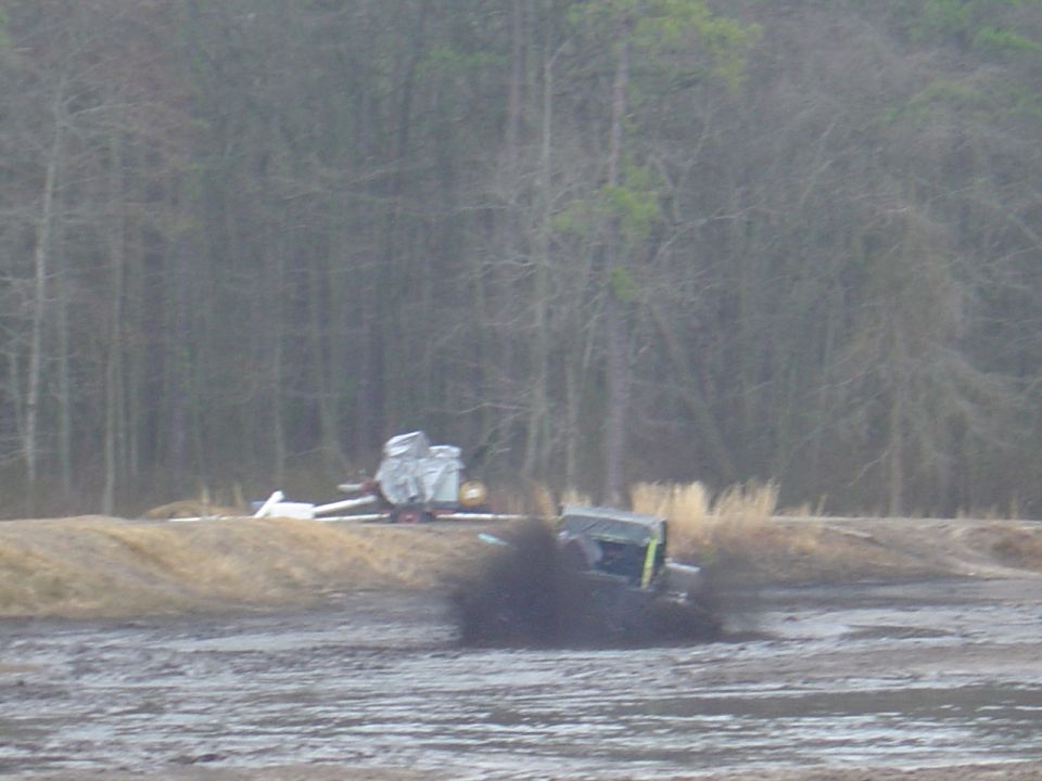 Jeep-like vehicle stuck in mud, kicking up a lot of dirt