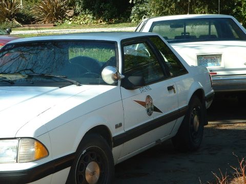 1987 Ford Mustang - This 1987 Ford Mustang, marked as 'SUPER PATROL', is seen from the side, with another vehicle behind it.