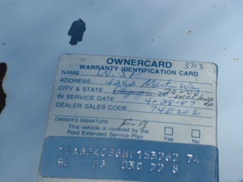 1987 Ford Mustang - A close-up of a vehicle's owner identification card with handwritten details and stamped codes.