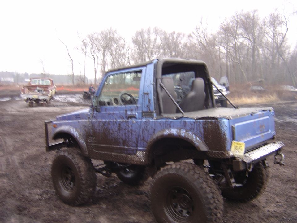 Blue 1987 Suzuki Samurai in mud, 3q-front view