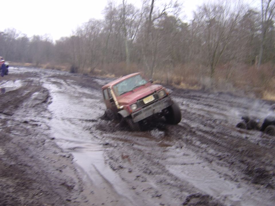 1987 Suzuki Samurai stuck in mud on an off-road trail. Another vehicle is visible in the background