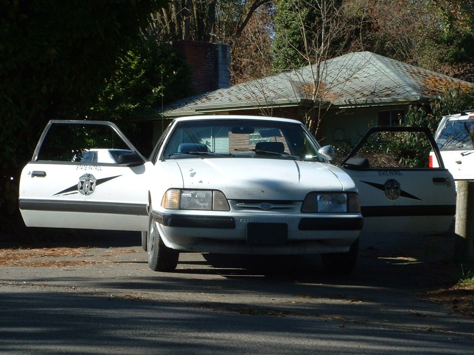 White 1987 Ford Mustang police car, front view, doors open, with 'PATROL' text on doors