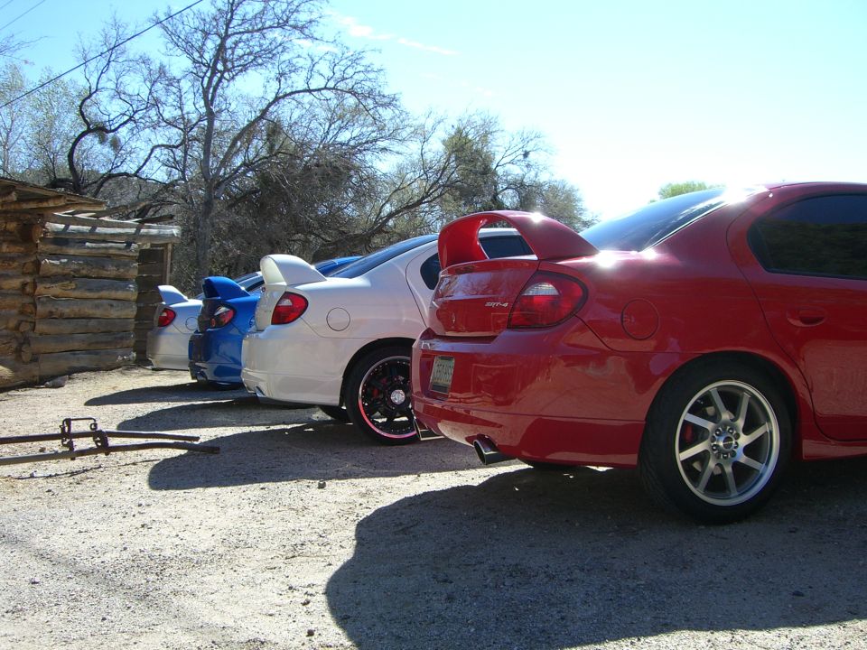Red sedan with a large rear spoiler parked in a line with other cars