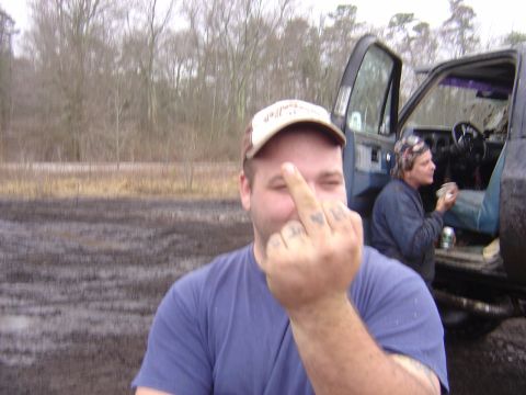 1987 Suzuki Samurai - A man gestures with his middle finger in front of a muddy outdoor scene with a truck.