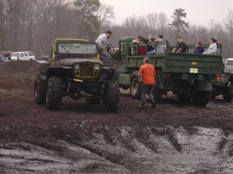 1987 Suzuki Samurai - Two off-road vehicles, a modified jeep and a military truck, are stuck in the mud.