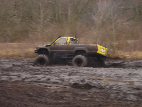 1987 Suzuki Samurai - Pickup truck with oversized tires stuck in thick mud during an off-road event.