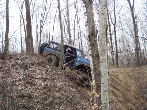 1974 Ford Bronco - Blue 1974 Ford Bronco navigating an off-road trail in a wooded area.