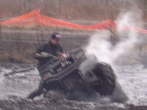 1987 Suzuki Samurai - An ATV is stuck in the mud, with a driver attempting to maneuver it while steam rises.