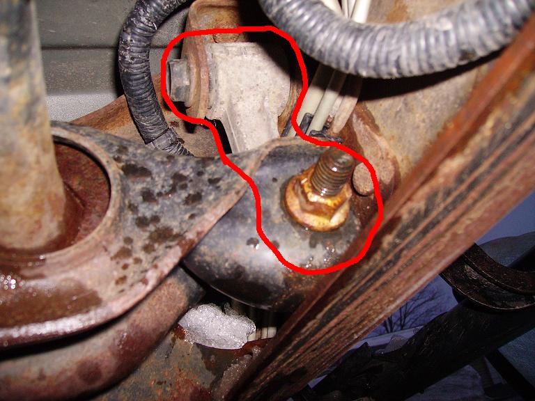 Rusted suspension part with bolt and wiring, circled in red