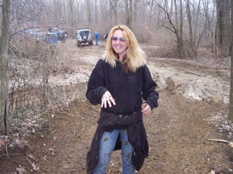 1974 Ford Bronco - A woman poses in a muddy off-road trail, with several off-road vehicles visible in the background.