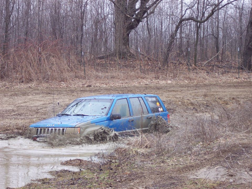Blue Jeep Grand Cherokee stuck in mud, front wheels submerged