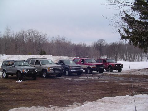 1994 Ford Bronco - Several SUVs and trucks are parked in a line on a snowy day.