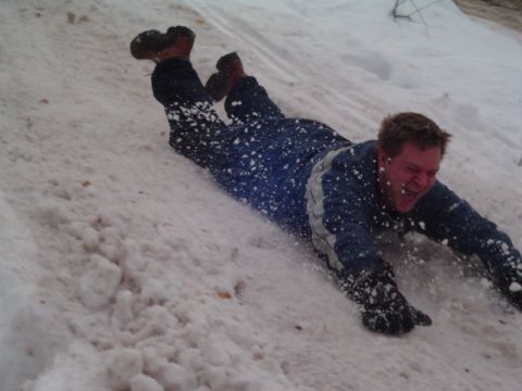 1994 Ford Bronco - A man slides down a snow-covered slope, kicking up snow as he goes.