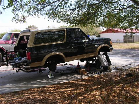 1988 Ford Bronco - Two vehicles are present, with one Ford Bronco undergoing suspension work on jack stands.