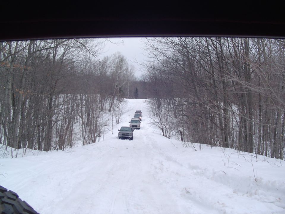 Line of SUVs driving up a snow-covered hill, seen from inside a vehicle
