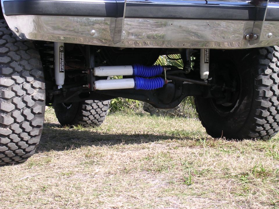 Rear axle with dual shocks and large tires. Supermotors.net logo visible