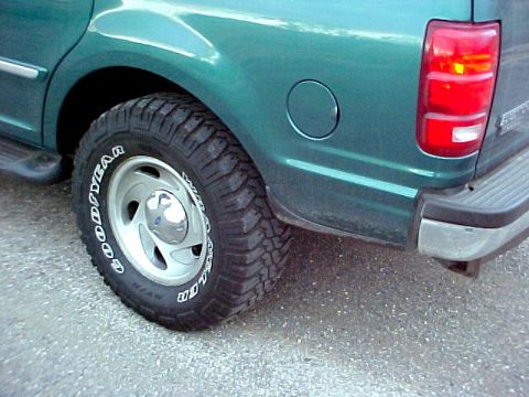 1997 Ford Expedition - Close-up of a green SUV's rear tire and body panel, showing the fuel door and taillight assembly.