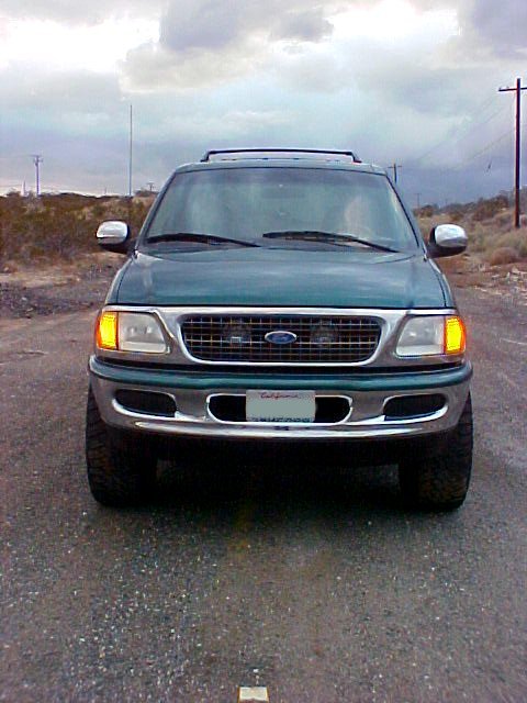 1997 Ford Expedition - A 1997 Ford Expedition is seen from the front, parked on a gravel road in a desert environment under a cloudy sky.