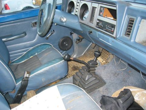 1991 Ford Explorer - The interior of a blue Ford Bronco II shows a manual transmission, dashboard, and worn seats.
